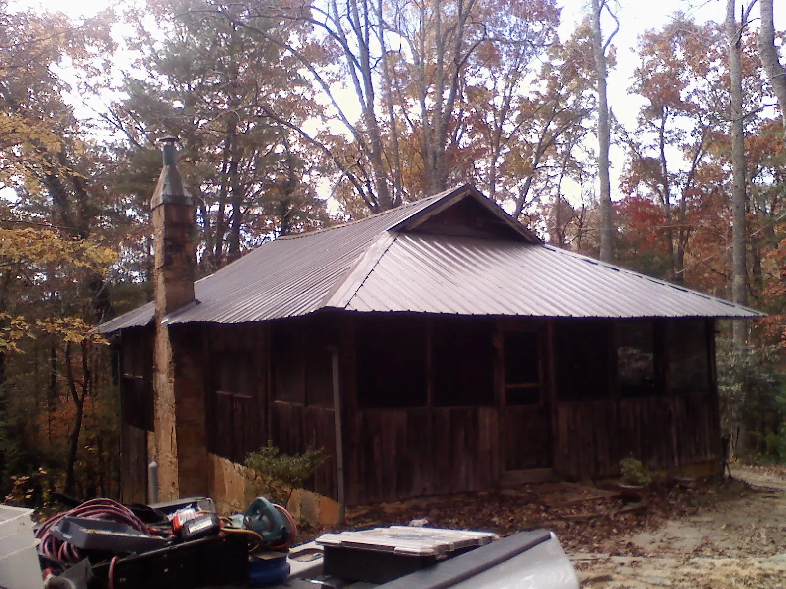 Brown metal hip roof on an old cabin with a stone chimney in West Point